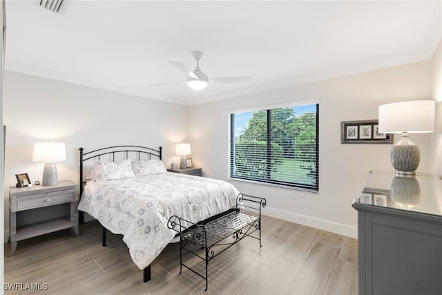 bedroom with light wood-style flooring, visible vents, a ceiling fan, baseboards, and crown molding