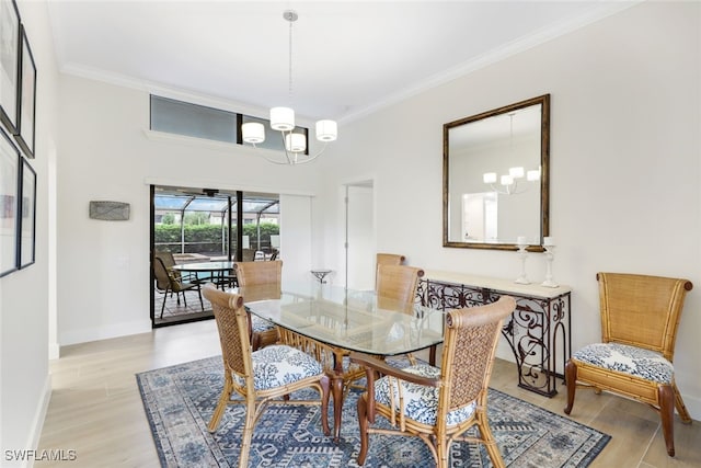 dining room featuring crown molding, light wood-type flooring, baseboards, and an inviting chandelier