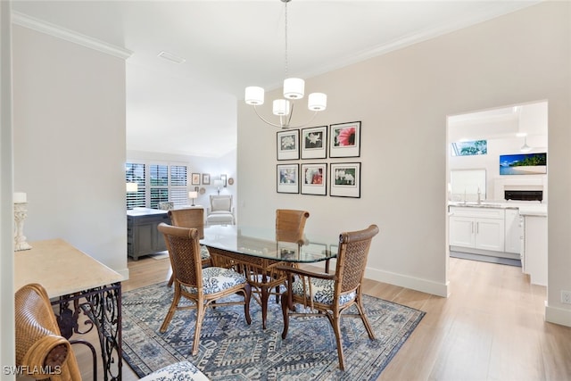 dining area with light wood-style floors, a chandelier, crown molding, and baseboards