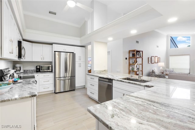 kitchen with visible vents, appliances with stainless steel finishes, white cabinetry, a sink, and light stone countertops