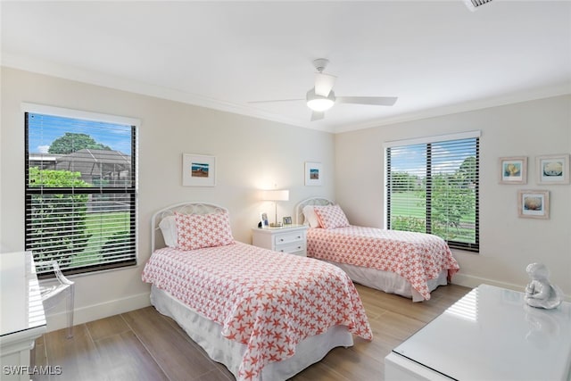 bedroom with ornamental molding, light wood finished floors, and baseboards