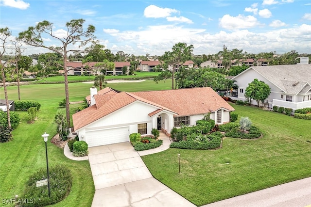 view of front of house featuring a garage, a residential view, concrete driveway, and a front yard