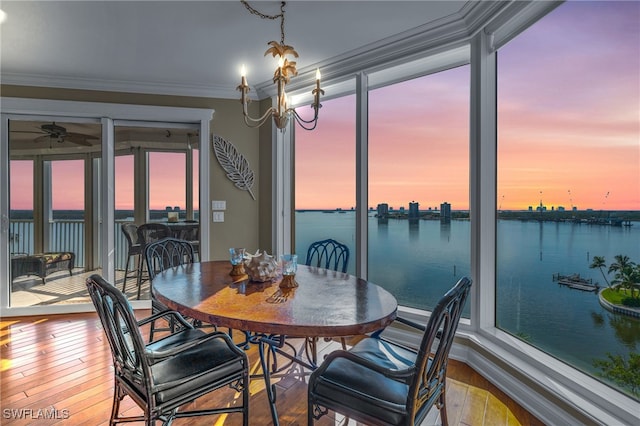 dining room featuring a water view, a healthy amount of sunlight, wood-type flooring, and crown molding