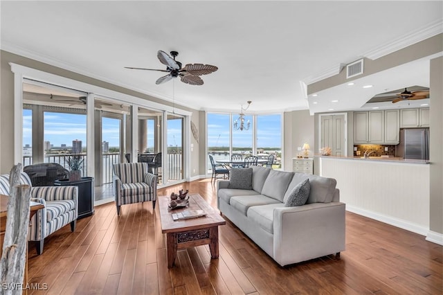 living room with crown molding, dark hardwood / wood-style floors, and ceiling fan with notable chandelier