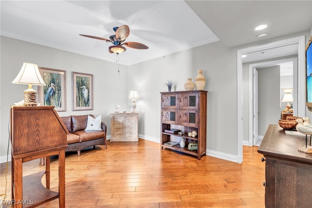 living area with crown molding, ceiling fan, and light wood-type flooring