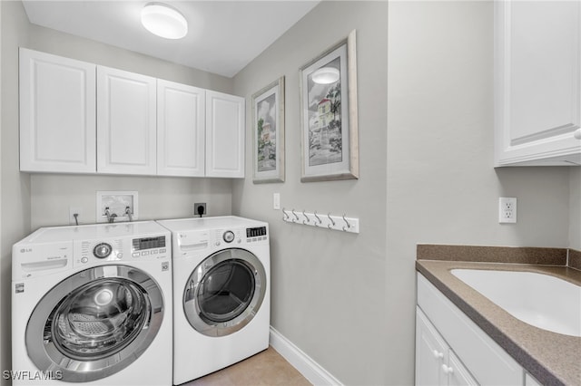 washroom with light tile patterned flooring, cabinets, sink, and washing machine and dryer