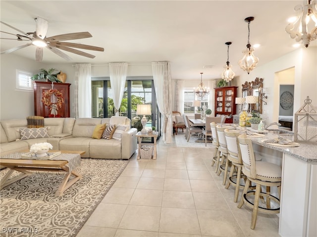 tiled living room with ceiling fan with notable chandelier and a healthy amount of sunlight