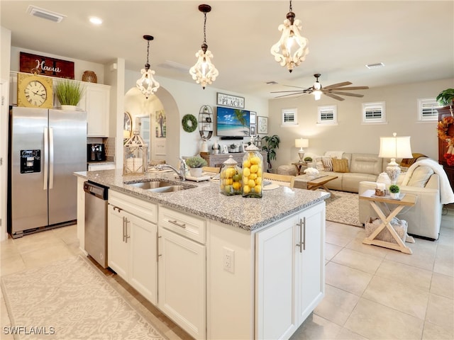 kitchen with hanging light fixtures, sink, a kitchen island with sink, white cabinetry, and appliances with stainless steel finishes