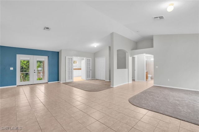 unfurnished living room with french doors, light tile patterned floors, and vaulted ceiling