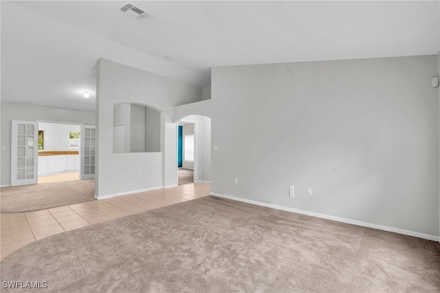 spare room featuring lofted ceiling and light tile patterned flooring