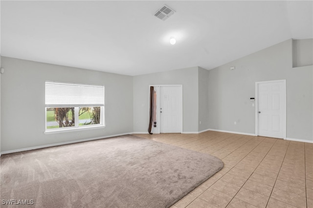 spare room with vaulted ceiling and light tile patterned floors