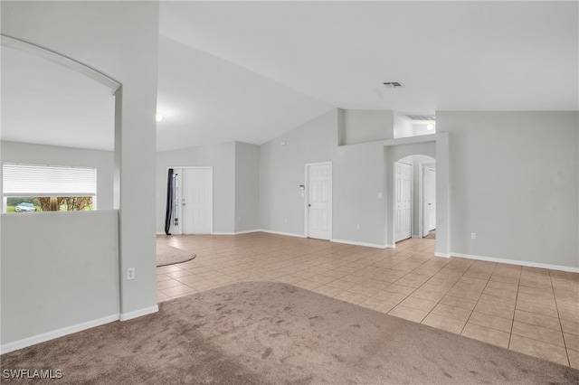 spare room featuring vaulted ceiling and light tile patterned flooring