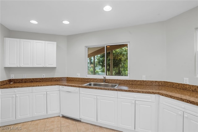 kitchen featuring white dishwasher, sink, white cabinetry, and light tile patterned flooring