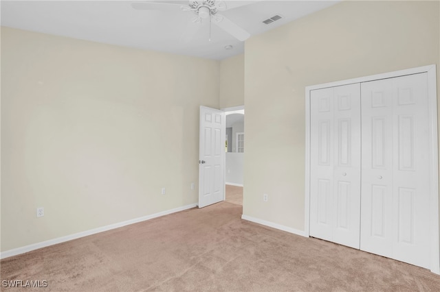 unfurnished bedroom featuring light carpet, ceiling fan, and a closet