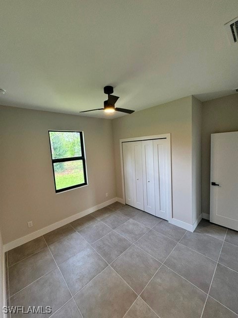 unfurnished bedroom with light tile patterned floors, ceiling fan, and a closet