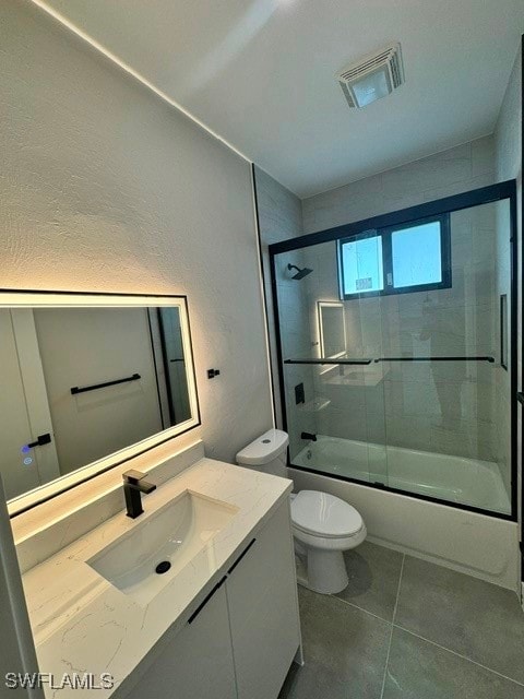 full bathroom featuring tile patterned floors, toilet, bath / shower combo with glass door, and vanity