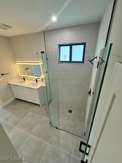 bathroom featuring tile patterned floors, tiled shower, and vanity