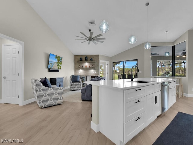 kitchen featuring a kitchen island with sink, sink, light hardwood / wood-style floors, white cabinetry, and hanging light fixtures