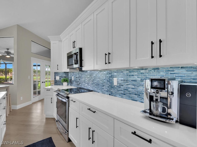 kitchen with decorative backsplash, white cabinetry, light hardwood / wood-style floors, and appliances with stainless steel finishes