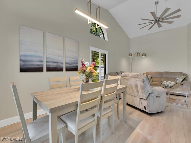 dining room with ceiling fan, light hardwood / wood-style floors, and high vaulted ceiling