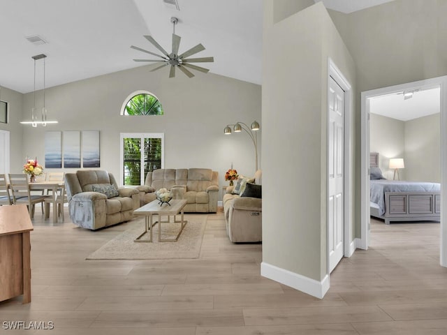 living room with ceiling fan, high vaulted ceiling, and light hardwood / wood-style floors