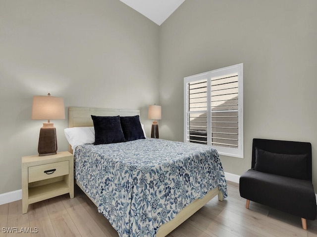 bedroom with light hardwood / wood-style flooring and high vaulted ceiling