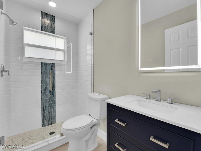 bathroom featuring vanity, toilet, and a tile shower