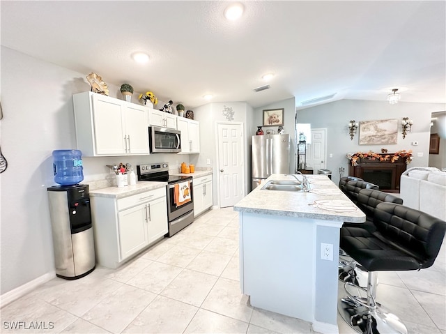 kitchen featuring lofted ceiling, open floor plan, light countertops, stainless steel appliances, and a sink