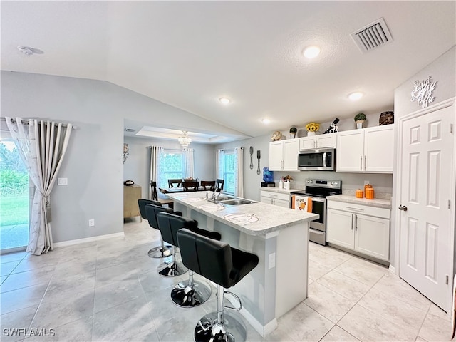 kitchen with a sink, visible vents, a kitchen breakfast bar, vaulted ceiling, and appliances with stainless steel finishes