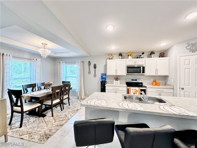 kitchen featuring white cabinets, stainless steel appliances, a sink, and light countertops