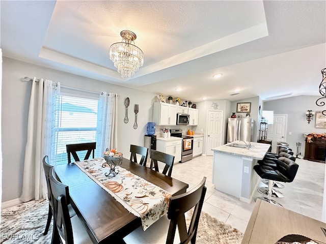 dining room with a raised ceiling, light tile patterned flooring, a textured ceiling, and an inviting chandelier