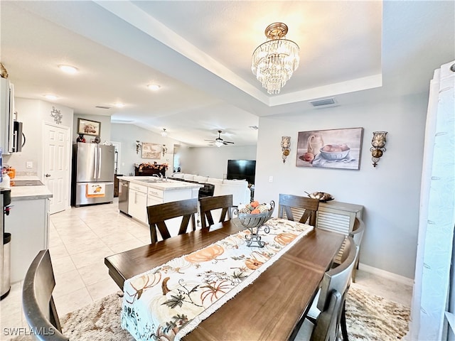 dining area with light tile patterned floors, lofted ceiling, visible vents, baseboards, and ceiling fan with notable chandelier