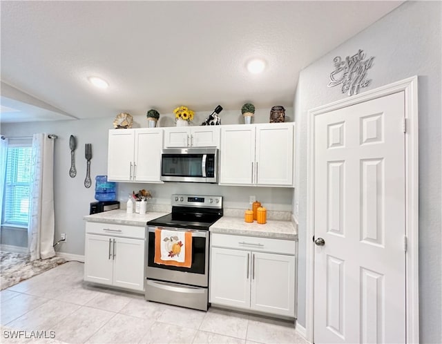 kitchen with light tile patterned floors, baseboards, white cabinets, stainless steel appliances, and light countertops