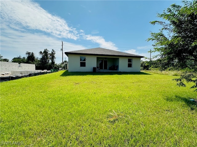 rear view of house with a lawn and stucco siding