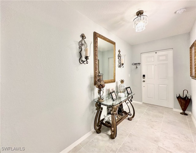 entryway with light tile patterned floors, an inviting chandelier, and baseboards