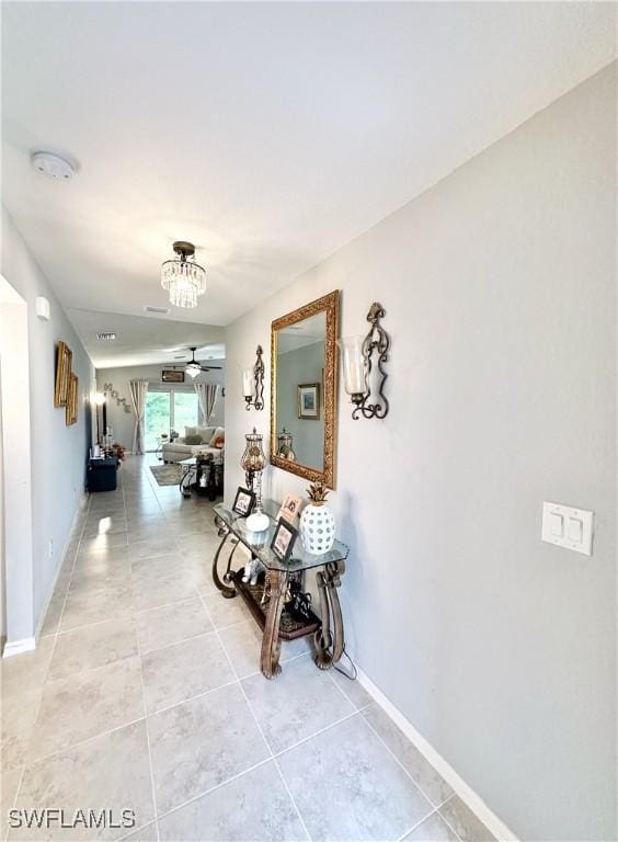 3214 68th St W, Lehigh Acres, FL 33971 - corridor featuring light tile patterned floors, baseboards, and a chandelier