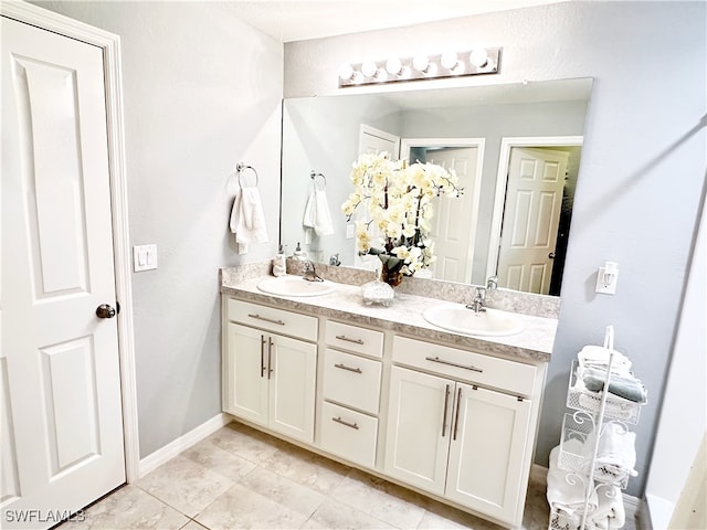 bathroom featuring double vanity, a sink, and baseboards