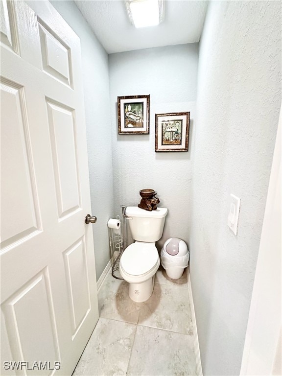 bathroom with toilet and baseboards