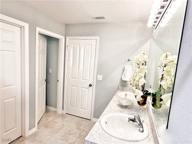 bathroom featuring double vanity, baseboards, visible vents, a textured ceiling, and a sink