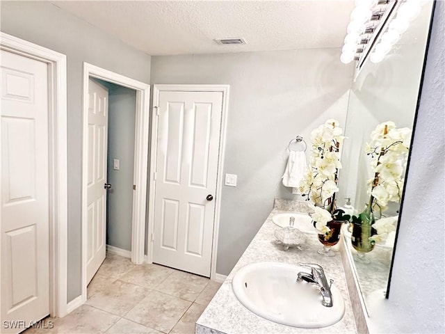 3214 68th St W, Lehigh Acres, FL 33971 - bathroom featuring double vanity, tile patterned flooring, a textured ceiling, and baseboards