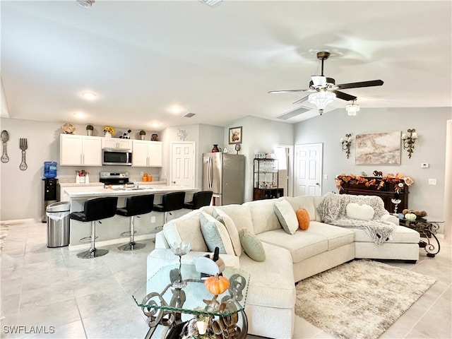 living area featuring vaulted ceiling, light tile patterned floors, and a ceiling fan