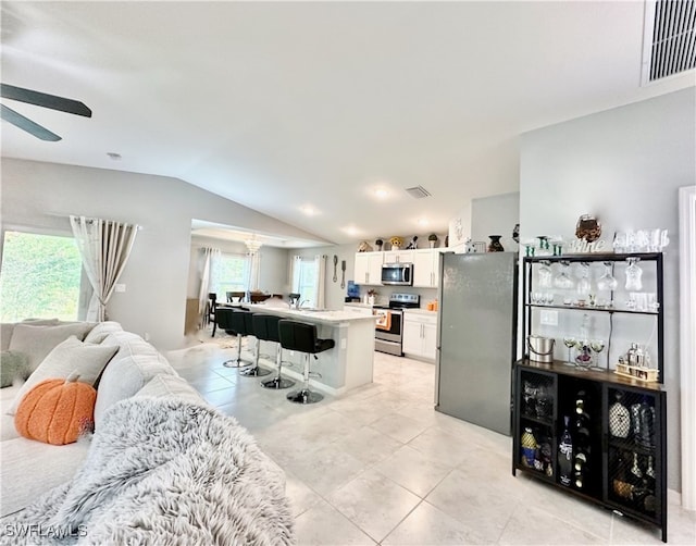 living room with lofted ceiling, light tile patterned floors, and visible vents