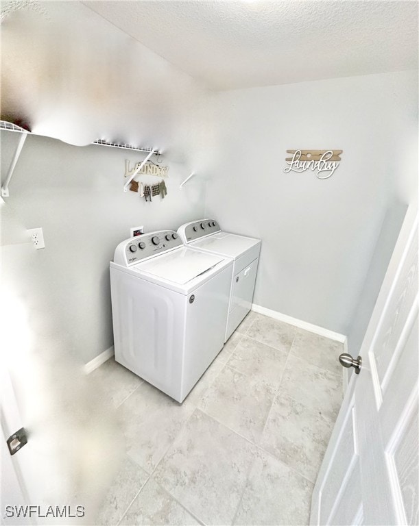 laundry area with a textured ceiling, laundry area, washing machine and clothes dryer, and baseboards