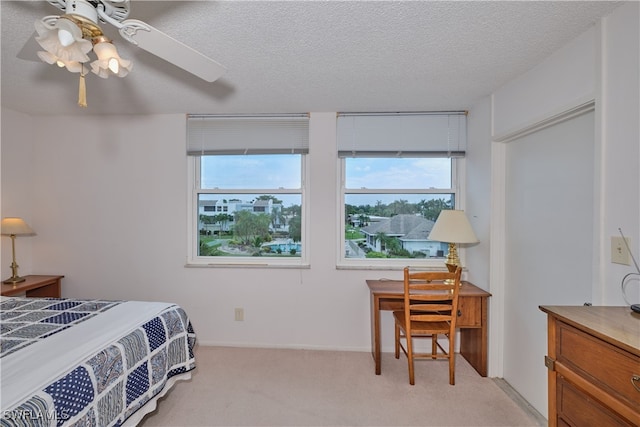 bedroom with ceiling fan, a textured ceiling, and light carpet