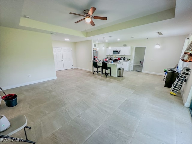 living room featuring ceiling fan and a raised ceiling