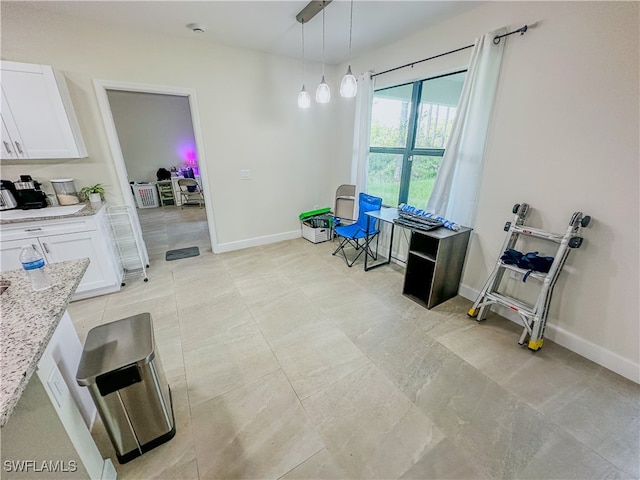 kitchen featuring light stone counters, hanging light fixtures, light tile patterned floors, and white cabinetry