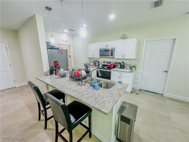 kitchen featuring pendant lighting, white cabinets, a kitchen breakfast bar, stainless steel appliances, and light stone countertops