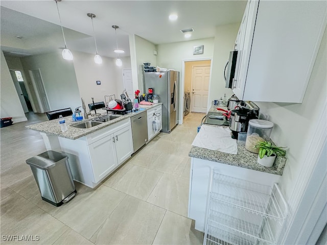 kitchen with appliances with stainless steel finishes, hanging light fixtures, light stone counters, white cabinets, and sink