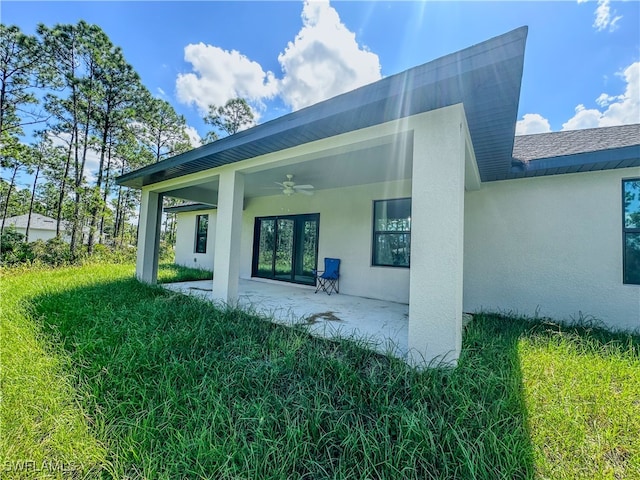 view of side of home with ceiling fan, a lawn, and a patio area