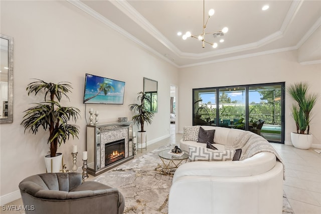 living room with a fireplace, crown molding, light tile patterned floors, an inviting chandelier, and a tray ceiling